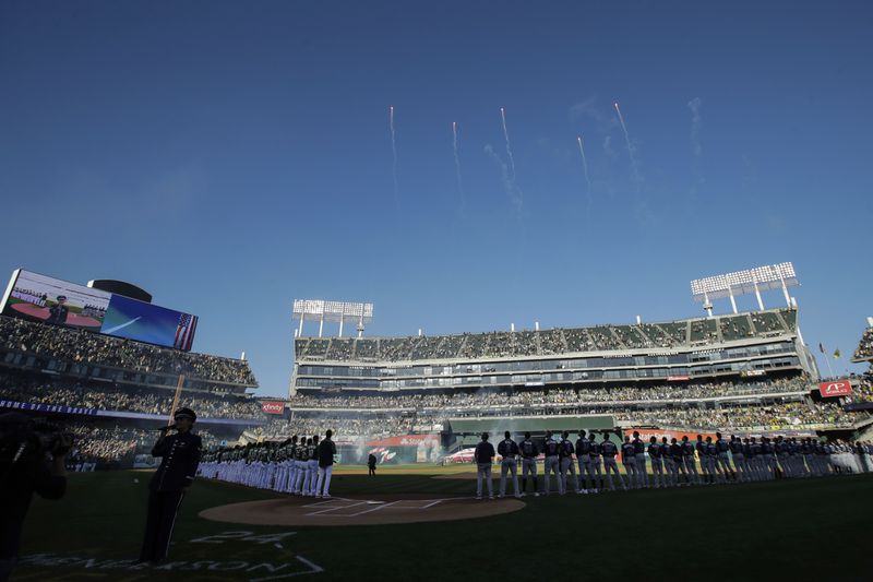 FILE - Fans at Oakland Coliseum listen as the national anthem is performed before an American League wild-card baseball game between the Oakland Athletics and the Tampa Bay Rays in Oakland, Calif., Wednesday, Oct. 2, 2019. (AP Photo/Jeff Chiu, File)