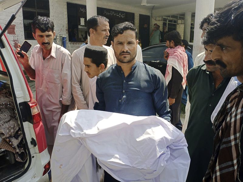 A relative carries body of a child, who was killed as a passenger bus fell into a ravine, at a hospital in Kahuta, Pakistan, Sunday, Aug. 25, 2024. (AP Photo/Mohammad Yousaf)