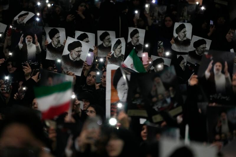 Mourners hold up a posters of the late Iranian President Ebrahim Raisi at the mam Khomeini Grand Mosque in Tehran, Iran, Tuesday, May 21, 2024, during a funeral ceremony for him and his companions who were killed in a helicopter crash on Sunday in a mountainous region of the country's northwest. Mourners in black began gathering Tuesday for days of funerals and processions for Iran's late president, foreign minister and others killed in a helicopter crash, a government-led series of ceremonies aimed at both honoring the dead and projecting strength in an unsettled Middle East. (AP Photo/Vahid Salemi)