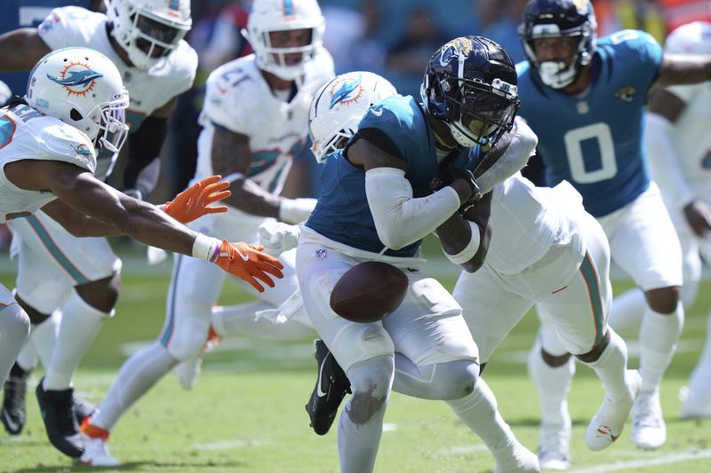 Jacksonville Jaguars running back Travis Etienne Jr. (1) fumbles the ball during the second half of an NFL football game against the Miami Dolphins, Sunday, Sept. 8, 2024, in Miami Gardens, Fla. (AP Photo/Wilfredo Lee)