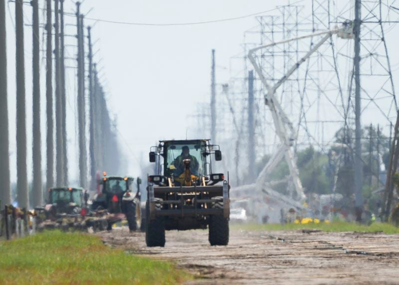 Large vehicles make their way from a make-shift road between utility lines toward East Pasadena Boulevard as an above-ground valve continues to burn three days after after a vehicle drove through a fence along a parking lot and struck the site, Wednesday, Sept. 18, 2024, in La Porte, Texas. (Jason Fochtman/Houston Chronicle via AP)