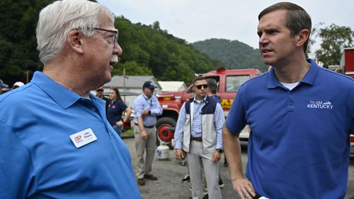 Kentucky Gov. Andy Beshear, right, speaks with John Pearce with the Appalachian Service Project before a ceremony to present the keys to 11 new homes to families displaced by flooding 2 years ago at the Wayland Volunteer Fire Station in Wayland, Ky., Friday, July 26, 2024. (AP Photo/Timothy D. Easley)