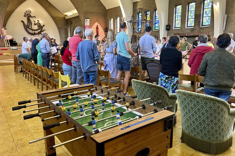 Parishioners stand together during a service at the Don Bosco Church in Buizingen, Belgium, Sunday, Sept. 1, 2024. (AP Photo/Raf Casert)