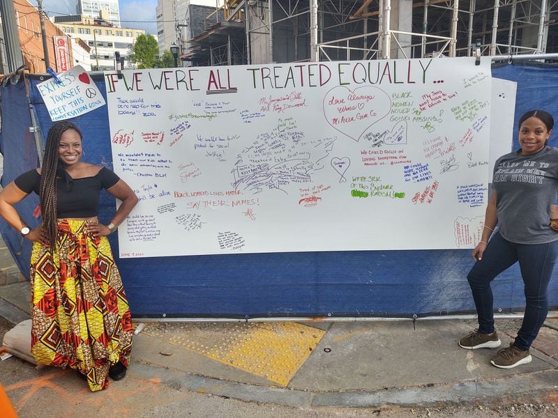 Amisha Harding, left, and her cousin Samantha Harding, have been bringing a "healing wall" to the downtown protests for people to sign. But she still fears for the safety of her  18-year-old son.