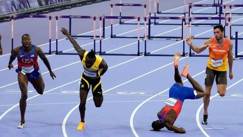 Grant Holloway, left, of the United States, wins the men's 110-meters hurdles final as teammate Daniel Roberts, takes a tumble at the line, at the 2024 Summer Olympics, Thursday, Aug. 8, 2024, in Saint-Denis, France. (AP Photo/Martin Meissner)