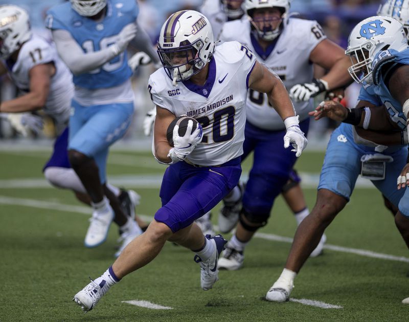 James Madison running back Tyler Purdy (20) finds a route through traffic during the second half of an NCAA college football game against North Carolina in Chapel Hill, N.C., Saturday, Sept. 21, 2024. (Daniel Lin/Daily News-Record via AP)