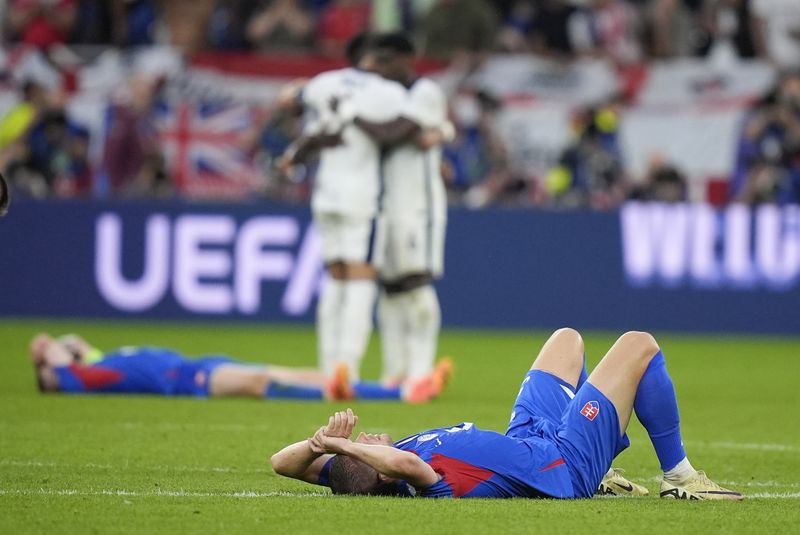 Slovakia players lie on the pitch after a round of sixteen match between England and Slovakia at the Euro 2024 soccer tournament in Gelsenkirchen, Germany, Sunday, June 30, 2024. (AP Photo/Matthias Schrader)