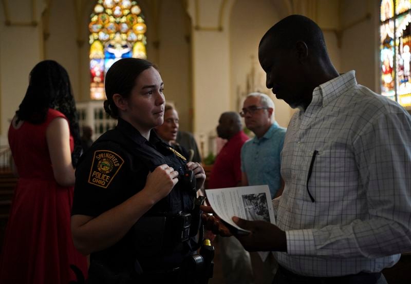 A Springfield police officer talks to a parishioner after a service in support of the Haitian community at St. Raphael Catholic church in Springfield, Ohio, Sunday, Sept. 15, 2024. (AP Photo/Luis Andres Henao)