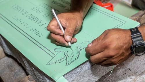 Mario Badillo uses a detail knife as he prepares a stone to be engraved while working at The Engraving House in Lithonia, Thursday, October 7, 2021. (Alyssa Pointer/ Alyssa.Pointer@ajc.com)