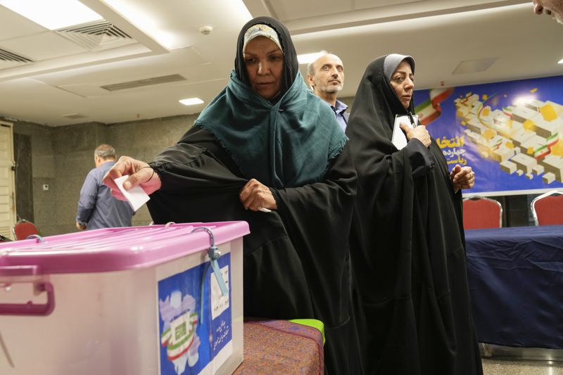 A woman casts her vote during the presidential election at a polling station inside the Iranian Embassy in Baghdad, Iraq, Friday, June 28, 2024. Iranians were voting Friday in a snap election to replace the late President Ebrahim Raisi, killed in a helicopter crash last month, as public apathy has become pervasive in the Islamic Republic after years of economic woes, mass protests and tensions in the Middle East. (AP Photo/Hadi Mizban)