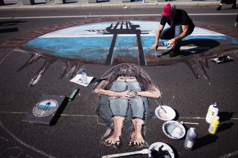 A man works on a painting as he takes part in a Global Climate Strike protest of the Fridays For Future movement near the chancellery in Berlin, Germany, Friday, Sept. 20, 2024. (AP Photo/Markus Schreiber)