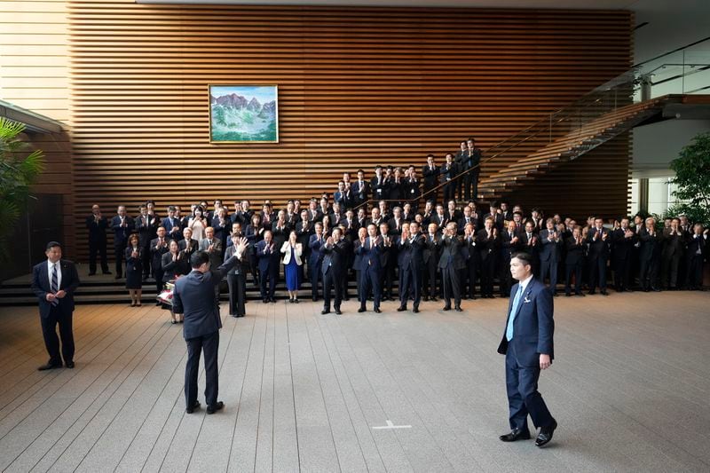 Japan's outgoing Prime Minister Fumio Kishida, center left showing his back, waves towards staff members and politicians as he leaves the prime minister's office in Tokyo Tuesday, Oct. 1, 2024. (AP Photo/Hiro Komae)