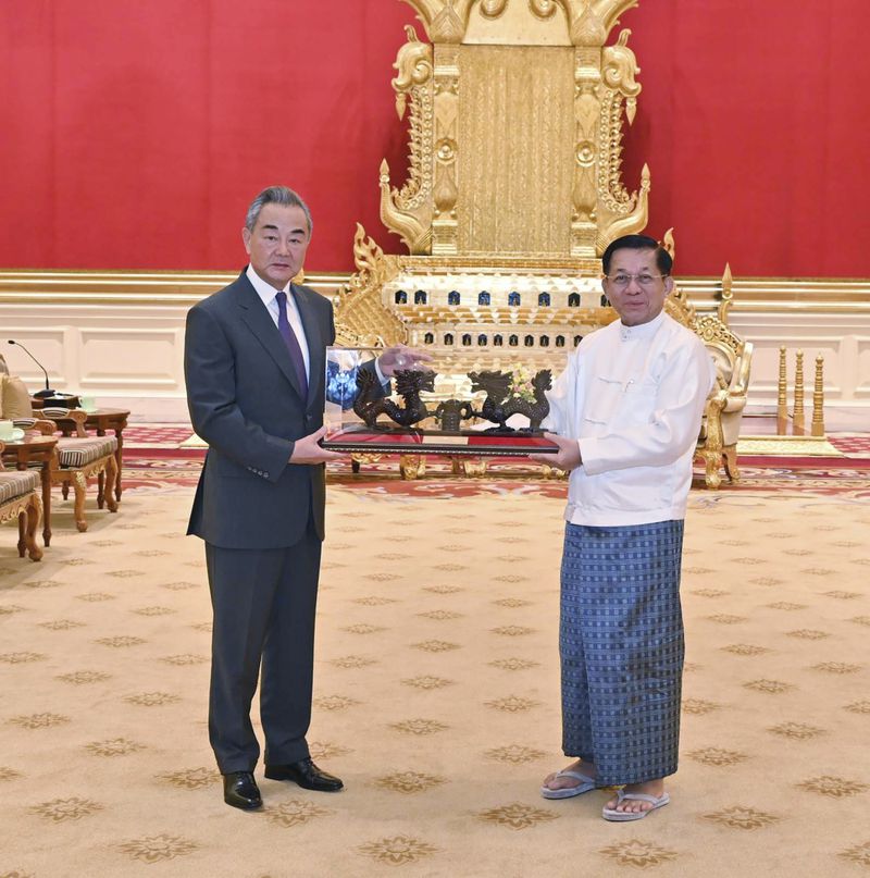 This photo provided by Myanmar Military Information Team, Myanmar's military leader Senior Gen. Min Aung Hlaing, right, chairman of State Administration Council, exchanges gift with Chinese Foreign Minister Wang Yi, left, during their meeting Wednesday, Aug. 14, 2024, in Naypyitaw, Myanmar. (Myanmar Military True News Information Team via AP)