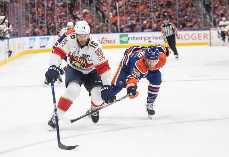 Florida Panthers' Aleksander Barkov (16) and Edmonton Oilers' Dylan Holloway (55) reach for the puck during the first period of Game 6 of the NHL hockey Stanley Cup Final, Friday, June 21, 2024, in Edmonton, Alberta. (Jason Franson/The Canadian Press via AP)