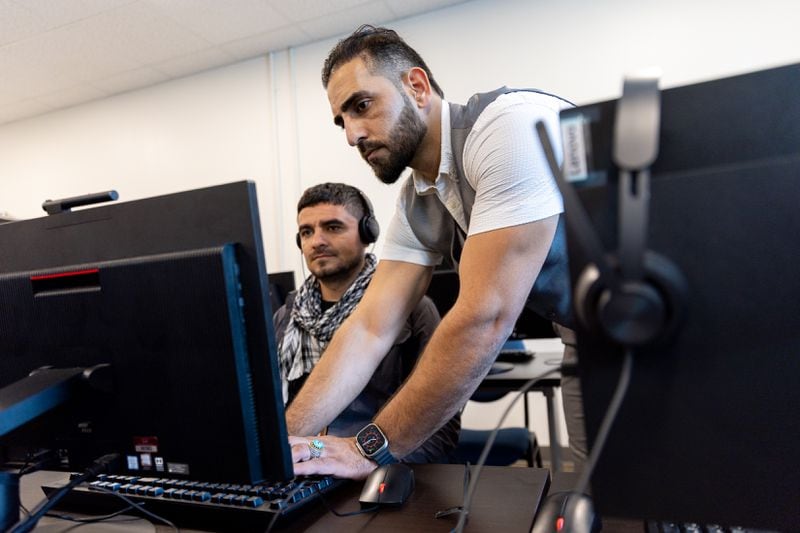Mirwais Jalali, a recruiter for aviation contractor Unifi, helps candidate Nametulah Sultani begin a computer training program at Unifi offices in Hapeville on Friday, April 19, 2024. (Arvin Temkar / arvin.temkar@ajc.com)