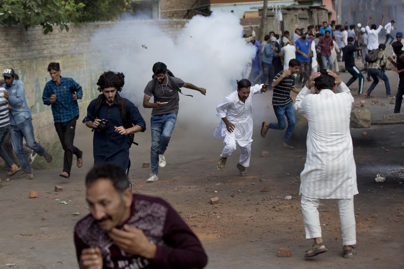 Kashmiris run for cover as a tear gas shell explodes near them during a protest in Srinagar Indian controlled Kashmir, Friday, Aug. 23, 2019. (AP Photo/ Dar Yasin, File)