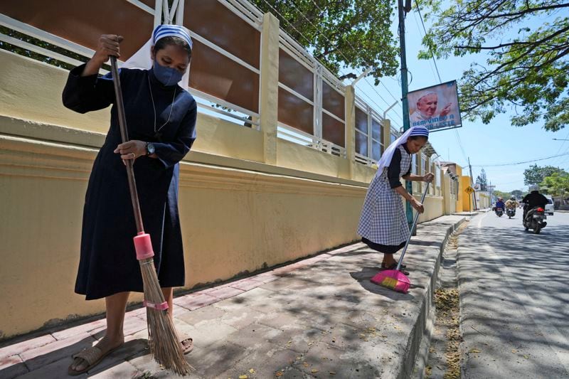 Catholic nuns sweep a sidewalk in Dili, East Timor, Monday, Aug. 12, 2024. (AP Photo/Achmad Ibrahim)