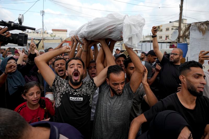 Palestinians mourn as they carry the body of a relative killed in the Israeli bombardment of the Gaza Strip at a hospital in Deir al-Balah, Tuesday, Oct. 8, 2024. (AP Photo/Abdel Kareem Hana)