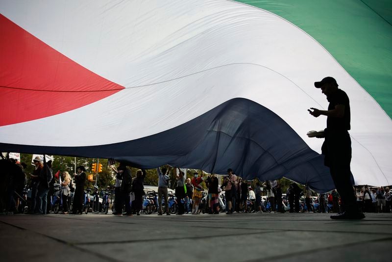 Pro-Palestinian protesters spread a Palestinian flag while demonstrating outside City Hall, Monday, Oct. 7, 2024, in New York. (AP Photo/Stefan Jeremiah)