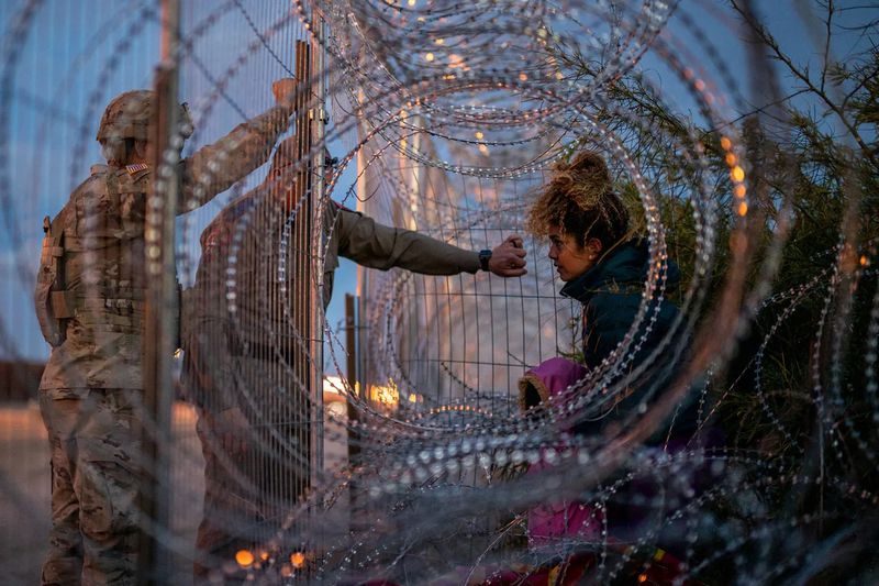 A 22-year-old migrant from Venezuela holds her 3-year-old daughter while being denied entry after attempting to cross through concertina wire from the U.S. side of the Rio Grande River on March 26, 2024, in El Paso, Texas. (BRANDON BELL/GETTY IMAGES)