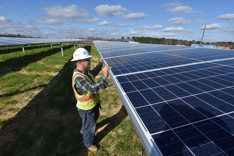 A worker with Solar Panel Solutions inspects solar equipment being installed in February in Bronwood, Ga. HYOSUB SHIN / HSHIN@AJC.COM