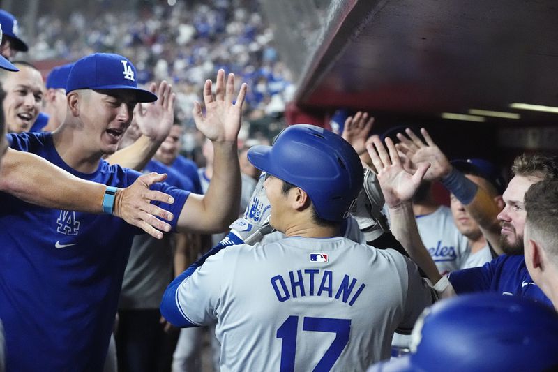 Los Angeles Dodgers designated hitter Shohei Ohtani, of Japan, celebrates his home run against the Arizona Diamondbacks in the dugout with teammates during the eighth inning of a baseball game Friday, Aug. 30, 2024, in Phoenix. (AP Photo/Ross D. Franklin)