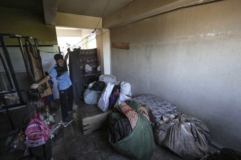 A Palestinian packs up to evacuate a school that had been his shelter, in eastern Deir al-Balah, Gaza Strip, Friday, Aug. 16, 2024, after the Israeli military dropped leaflets asking civilians to evacuate from the area, saying forces plan to respond to rocket fire that targeted Israel. (AP Photo/Abdel Kareem Hana)