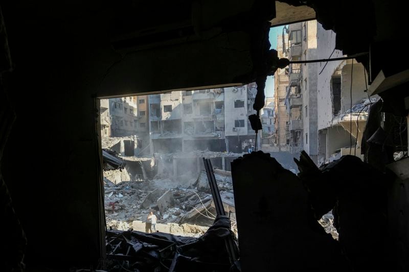 People check the site of an Israeli airstrike in Beirut's southern suburbs, Sunday, Sept. 29, 2024. (AP Photo/Hassan Ammar)