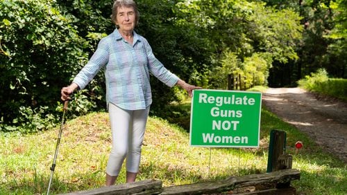 Mary Ellen Myers, a member of the Banks County Democratic Committee, poses with a sign she used to display in her yard in Alto. Myers said she found trash, such as drink cans, thrown at the sign, although she's faced little other backlash. “There’s some civility in this county,” said Myers, who has lived in Banks County for more than two decades. (Seeger Gray / AJC)