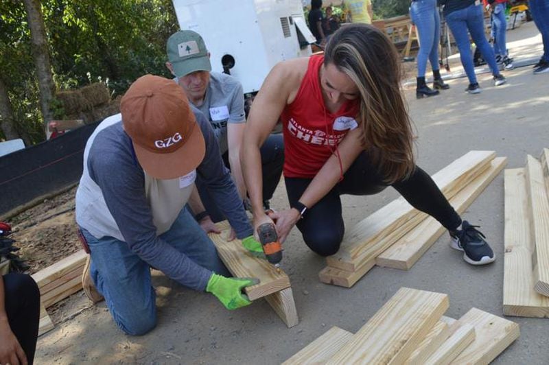 An Atlanta Falcons cheerleader uses a power screwdriver to help build part of the PlayTown Suwanee playground at the Suwanee Town Center on Main park site on Tuesday. (Photo Courtesy of Curt Yeomans)