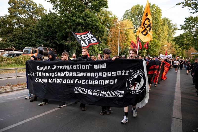 People carry a banner reads "Against "Remigration" and "Repatriation Improvement Act - Against War and Fascism" during a protest against an election party of AfD supporters for the state elections in Saxony and Thuringia, in Berlin, Germany, Sunday, Sept. 1, 2024. (Fabian Sommer/dpa via AP)