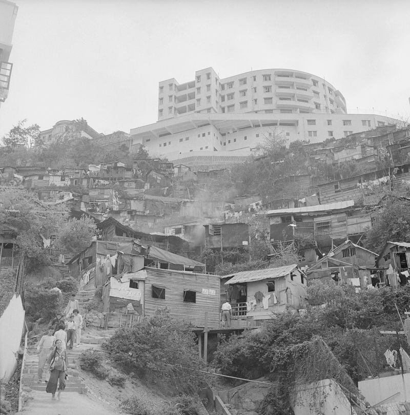 FILE- Perched high on a hill, a shiny new apartment house looks down upon a settlement of squatters' huts in the British crown colony of Hong Kong on May 16, 1956. (AP Photo/File)