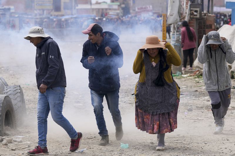 Supporters of former President Evo Morales run from tear gas thrown by police during clashes with supporters of current President Luis Arce in El Alto, Bolivia, Sunday, Sept. 22, 2024. (AP Photo/Juan Karita)