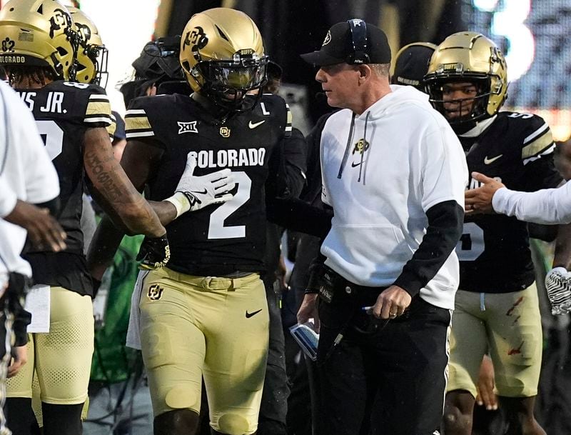 Colorado quarterback Shedeur Sanders (2) confers with offensive coordinator Pat Shurmur, center right, after running for a touchdown in the first half of an NCAA college football game against Baylor, Saturday, Sept. 21, 2024, in Boulder, Colo. (AP Photo/David Zalubowski)