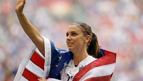 FILE - United States' Alex Morgan is draped in the U.S. flag as she waves to fans after the U.S. beat Japan 5-2 in the FIFA Women's World Cup soccer championship in Vancouver, British Columbia, Canada, Sunday, July 5, 2015. (AP Photo/Elaine Thompson, File)