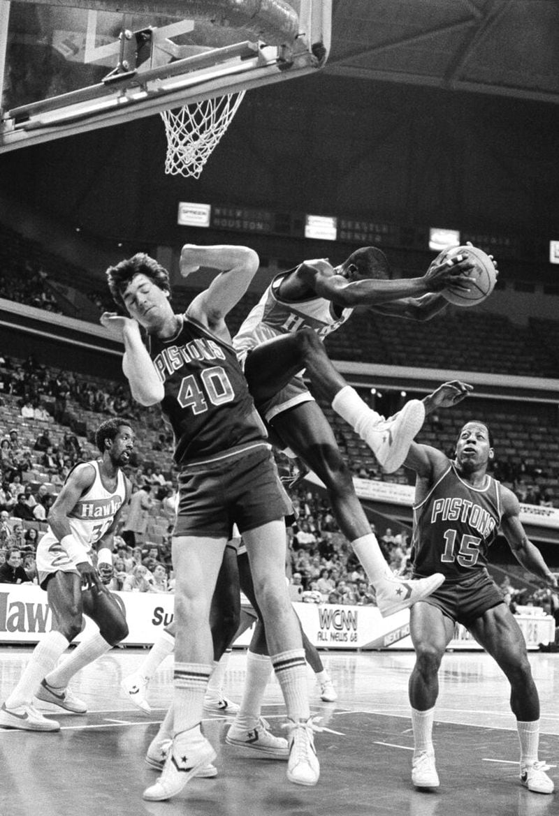 Atlanta Hawks Dominique Wilkings sails out with a rebound Thursday between Detroit Pistons center Bill Laimbeer (40) and guard Vinnie Johnson (15) at Atlanta Omni, February 24, 1983. At left is foreward Dan Roundfield of the hawks in their National Basketball Association game. (AP Photo/Ben Baxter)