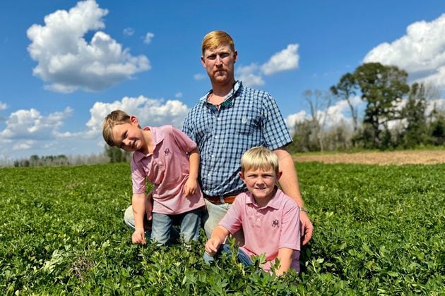 Peanut farmer Riley Davis sits in a peanut field along the Webster County border south of Plains with his sons, Drew (left), 4, and Luke, 7. (Joe Kovac Jr./AJC)