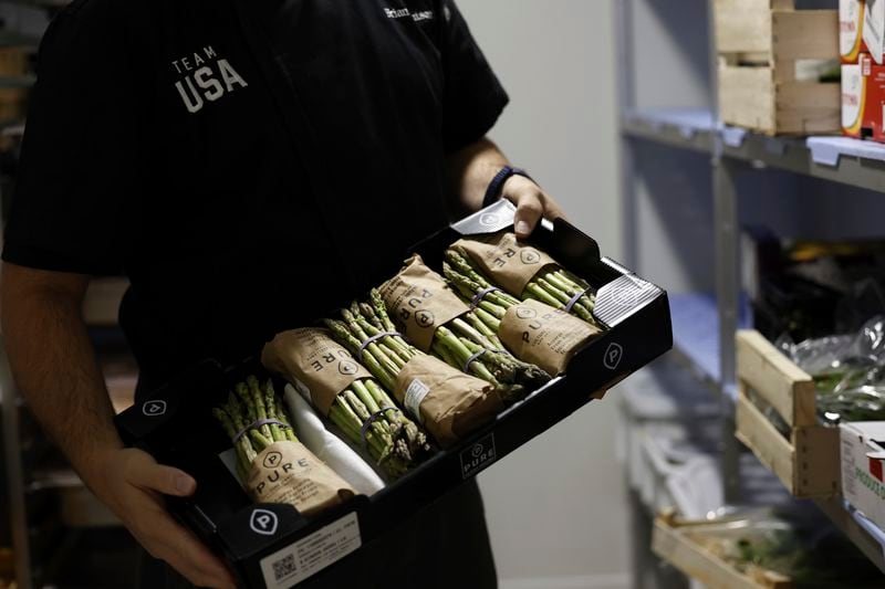 Brian Knutson, director of food and nutrition for the United States Olympic Paralympic Committee, holds up a crate of asparagus in the kitchen of the USOPC's High Performance Center on Saturday, Aug. 31, 2024. This is the first year that the HPC has been kept open for the Paralympic athletes. Knutson said that the quality of the local fruit and vegetables they were receiving were good. When they were in Tokyo, they realized that they were shipping raspberries from Oregon, Knutson said. (AP Photo/Nathalee Simoneau)