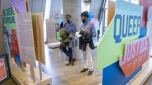 Elliott Abnatha (left) and Jai Kenon look over the traveling exhibit "Queer Justice: 50 Years of Lambda Legal and LGBTQ+ Rights" at the National Center for Civil and Human Rights Saturday, January 6, 2024. (Steve Schaefer/steve.schaefer@ajc.com)