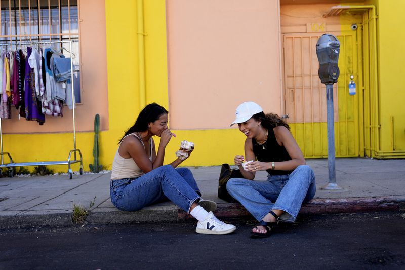 Nemesis R., left, and Zoe Abel sit and eat ice cream on a street in the Highland Park section of Los Angeles on Monday, Aug. 12, 2024, after an earthquake was strongly felt from the Los Angeles area all the way to San Diego. (AP Photo/Ryan Sun)