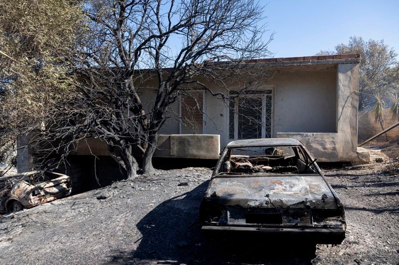 A burnt car is seen in the yard of a house after a wildfire at Keratea area, southeast of Athens, Greece, Sunday, June 30, 2024. (AP Photo/Yorgos Karahalis)