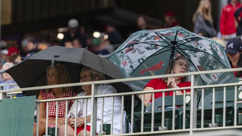 Baseball fans wait for the rain to pass before a baseball game between the St. Louis Cardinals and Atlanta Braves, Friday, July 19, 2024, in Atlanta. (AP Photo/Jason Allen)