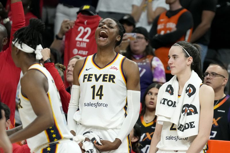 Indiana Fever center Temi Fagbenle (14) celebrates after a win over the Phoenix Mercury while standing next to Fever guard Caitlin Clark, right, in the closing seconds of the second half of a WNBA basketball game Sunday, June 30, 2024, in Phoenix. (AP Photo/Ross D. Franklin)