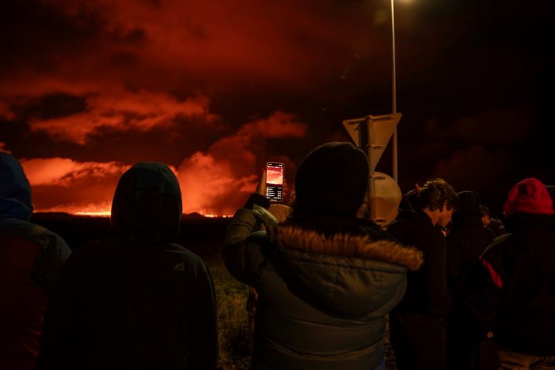 Tourists and visitors try to get a view of the eruption from a distance from the intersection between Reykjanesbraut, Iceland, and the road to Grindavik, Thursday, Aug. 22, 2024. (AP Photo/Marco di Marco)