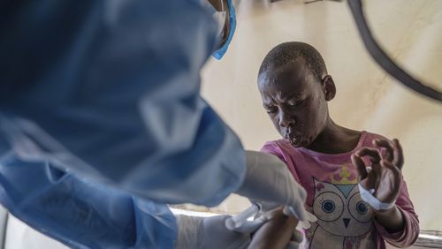 A health worker attends to a mpox patient, at a treatment centre in Munigi, eastern Congo, Monday, Aug. 19, 2024. Congo will receive the first vaccine doses to address its mpox outbreak next week from the United States, the country's health minister said Monday, days after the World Health Organization declared mpox outbreaks in Africa a global emergency. (AP Photo/Moses Sawasawa)