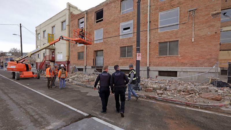 Police officers walk by rubble after a 5.7-magnitude earthquake near Salt Lake City.