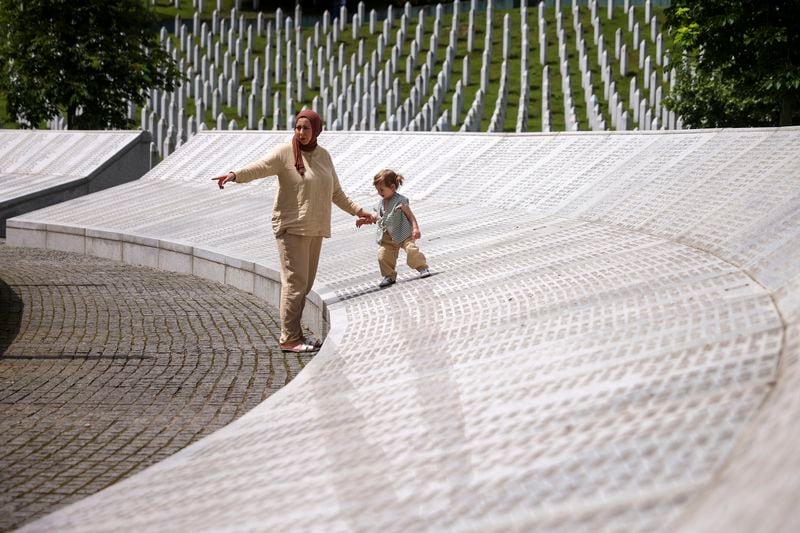 A child walks on the monument with the names of the victims in Srebrenica genocide, at the Memorial Center in Potocari, Bosnia, Wednesday, May 22, 2024. On May 23, the United Nations General Assembly will be voting on a draft resolution declaring July 11 the International Day of Reflection and Commemoration of the 1995 genocide in Srebrenica. (AP Photo/Armin Durgut)