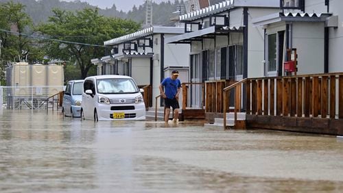 A man wades through a flooded street near temporary housing units installed after the Jan. 1 earthquake in Wajima, Japan, Sunday, Sept. 22, 2024, following heavy rain in central Japan's Noto peninsula area. (Muneyuki Tomari/Kyodo News via AP)