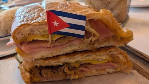 The pressed Cuban sandwich from Azucar Cuban Cuisine is a classic combination of slow-roasted pork, ham, Swiss cheese, dill pickles, mayonnaise and mustard. (Paula Pontes for The Atlanta Journal-Constitution)