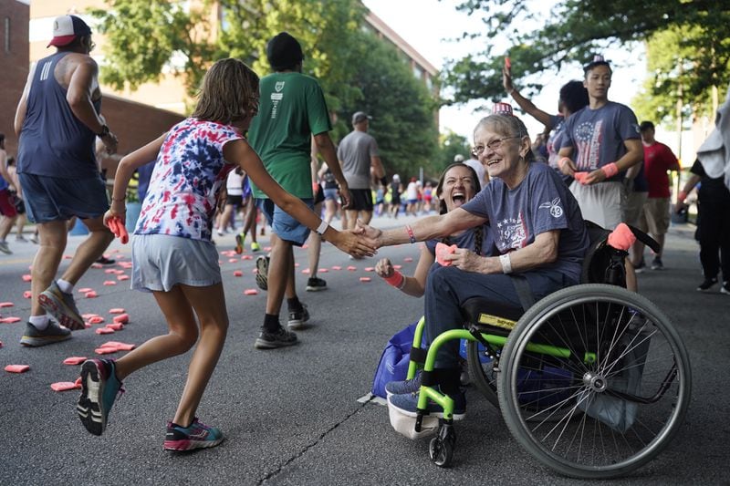 Patient at the Shepherd Center welcomes runners on Cardiac Hill along Peachtree Street during the 55th running of the Atlanta Journal-Constitution Peachtree Road Race in Atlanta on Thursday, July 4, 2024.   (Seeger Gray / AJC)